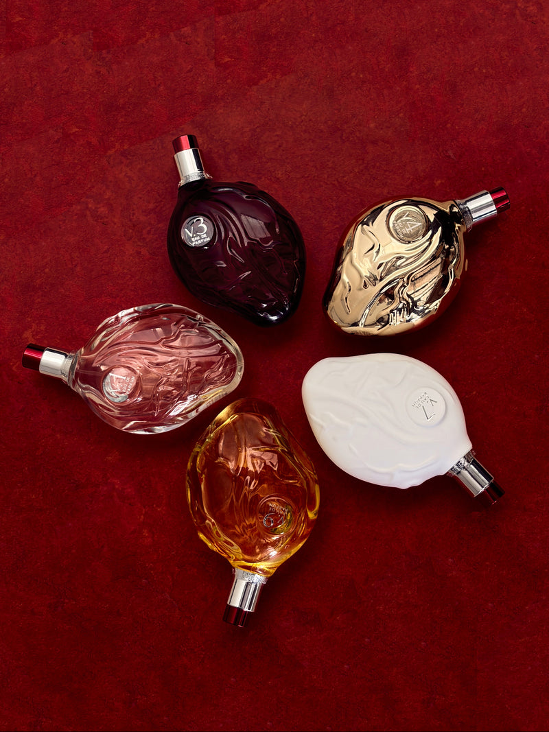 Five perfume bottles of different colors on a red background