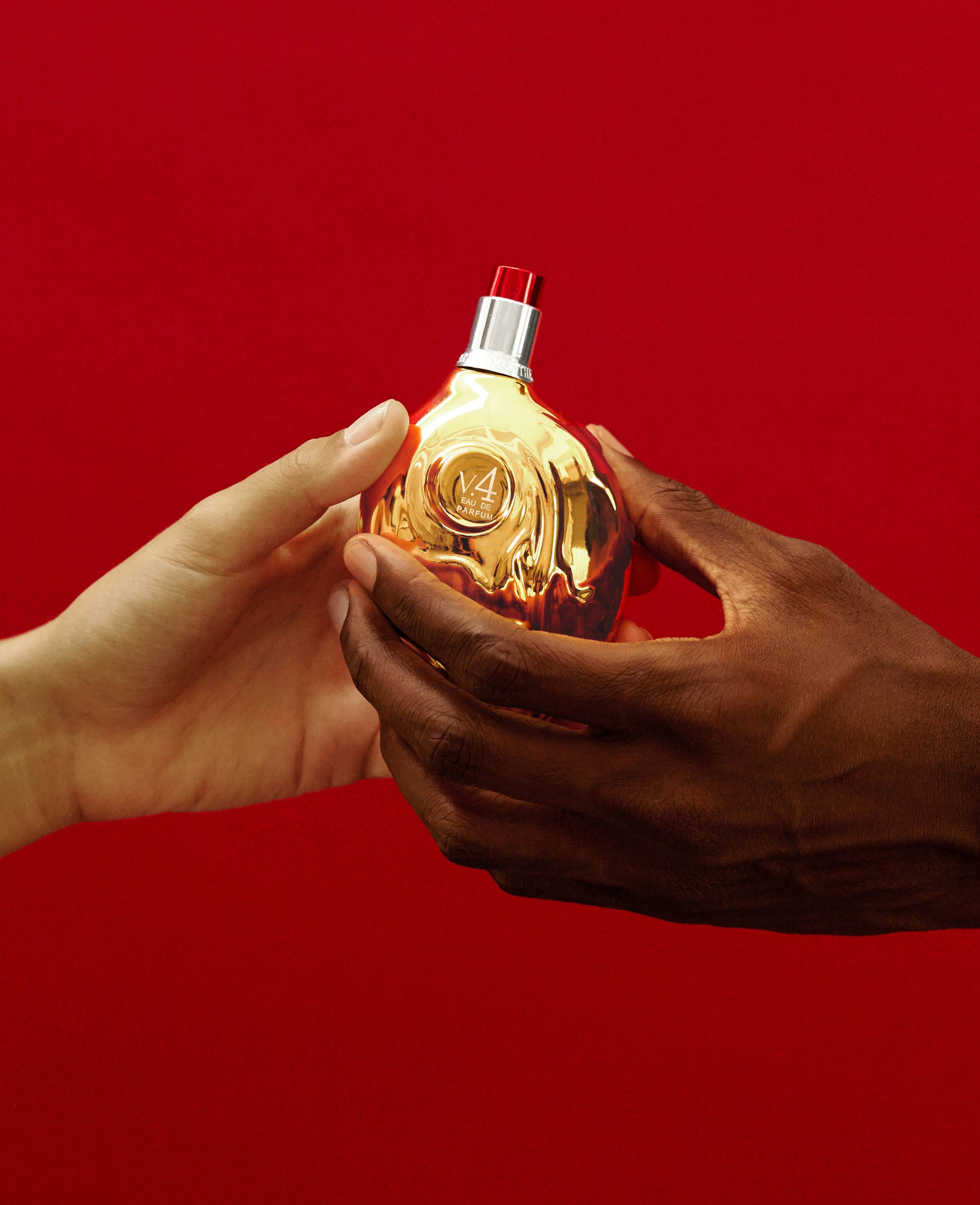 Hands holding Map of the Heart V.4 Peace eau de parfum in a gold heart-shaped glass bottle with red cap 90ml on red background
