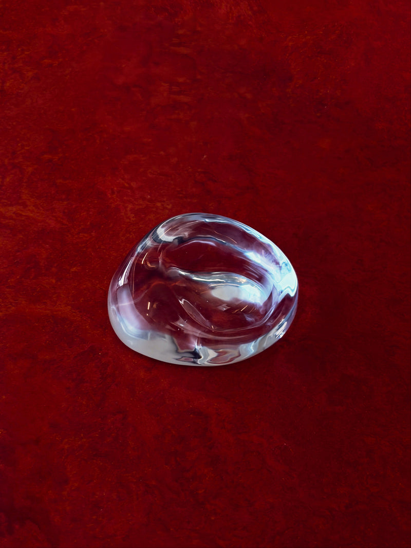 Clear glass perfume stand on a red textured surface