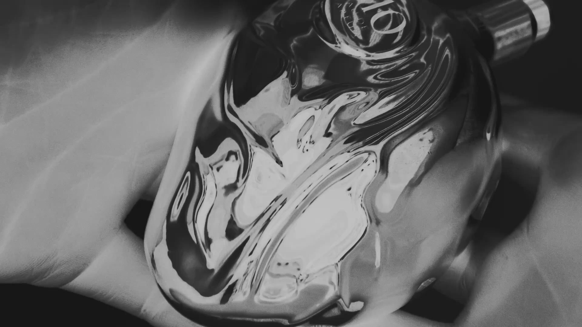 Map of the Heart V.10 Frisson campaign film in solarised black and white, with a torn rose and hands holding the silver heart bottle